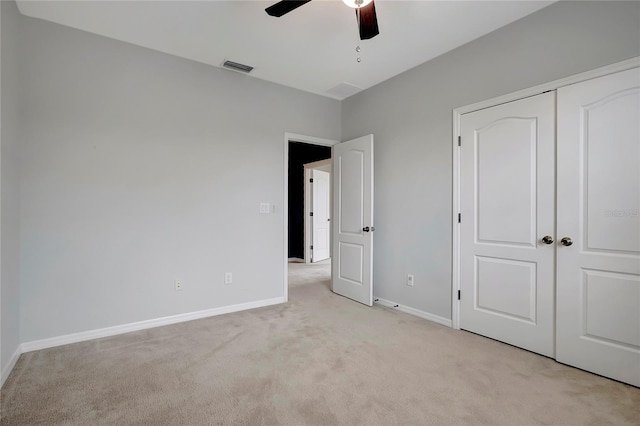 unfurnished bedroom featuring ceiling fan, a closet, and light carpet