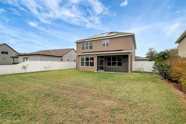 rear view of house with a lawn and solar panels