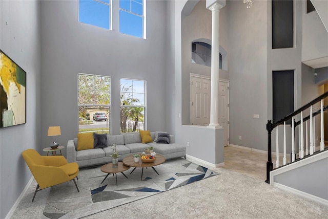 living room with light colored carpet, a towering ceiling, and decorative columns