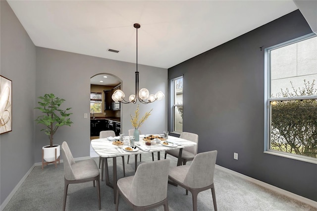 carpeted dining space featuring a notable chandelier, plenty of natural light, and sink