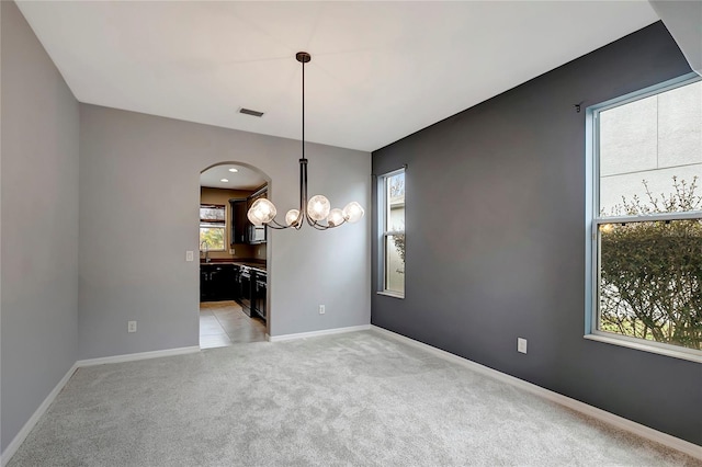 unfurnished dining area with light colored carpet, sink, plenty of natural light, and a notable chandelier