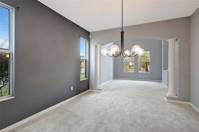 unfurnished dining area with light carpet, a chandelier, and decorative columns