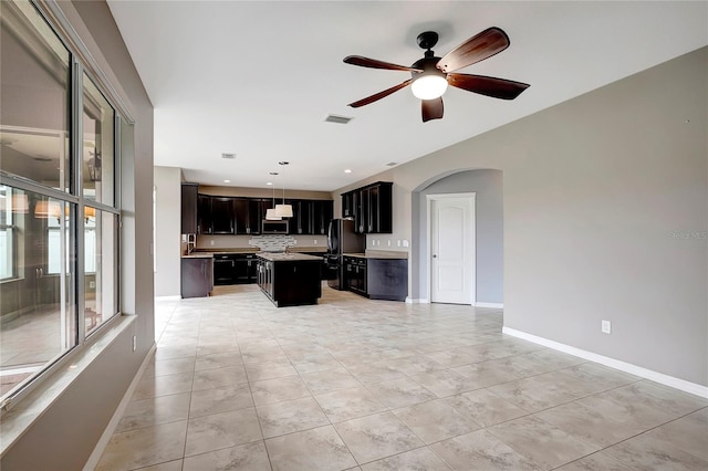 kitchen with pendant lighting, a center island, black refrigerator, ceiling fan, and light tile patterned floors