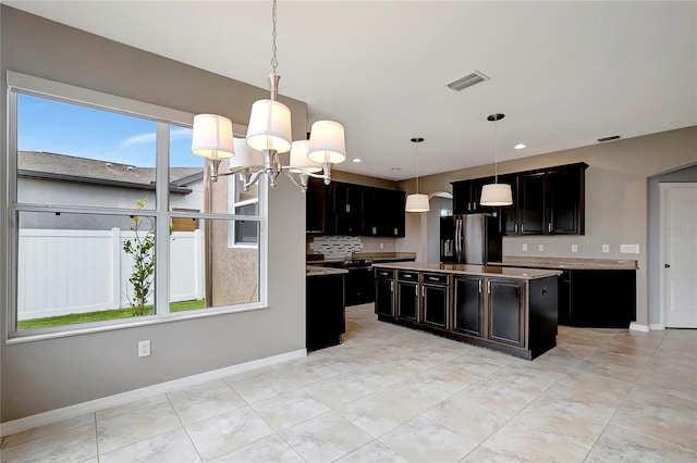 kitchen with pendant lighting, a center island, an inviting chandelier, backsplash, and stainless steel fridge