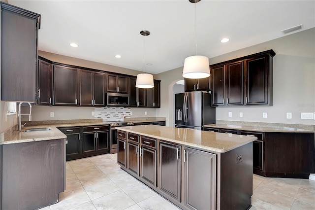 kitchen featuring a kitchen island, pendant lighting, sink, dark brown cabinetry, and appliances with stainless steel finishes