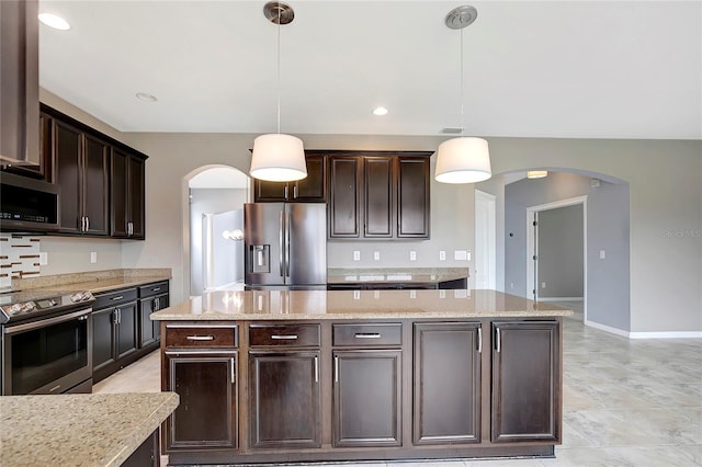 kitchen featuring pendant lighting, dark brown cabinetry, stainless steel appliances, and a kitchen island