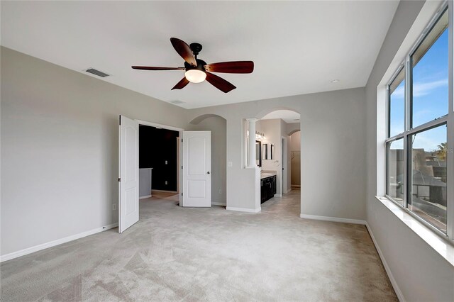 unfurnished bedroom featuring ensuite bathroom, light colored carpet, and ceiling fan