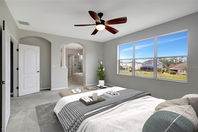 bedroom with ensuite bath, light colored carpet, ceiling fan, and decorative columns