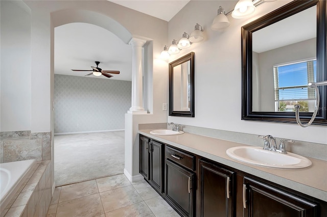 bathroom featuring ceiling fan, vanity, tile patterned floors, tiled tub, and ornate columns