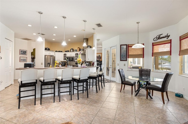 kitchen with white cabinets, pendant lighting, appliances with stainless steel finishes, and a kitchen breakfast bar