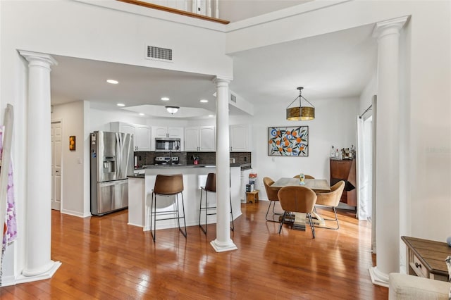 kitchen with white cabinetry, a breakfast bar, kitchen peninsula, pendant lighting, and appliances with stainless steel finishes