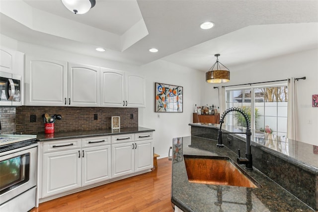 kitchen with sink, stainless steel appliances, white cabinets, and hanging light fixtures