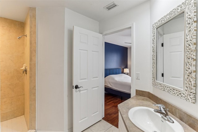 bathroom featuring tile patterned flooring, a tile shower, and vanity