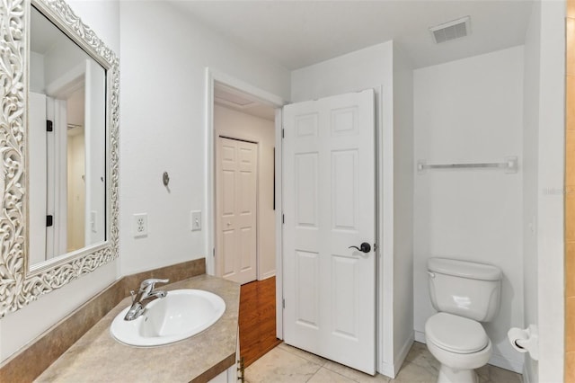 bathroom with toilet, tile patterned flooring, and vanity