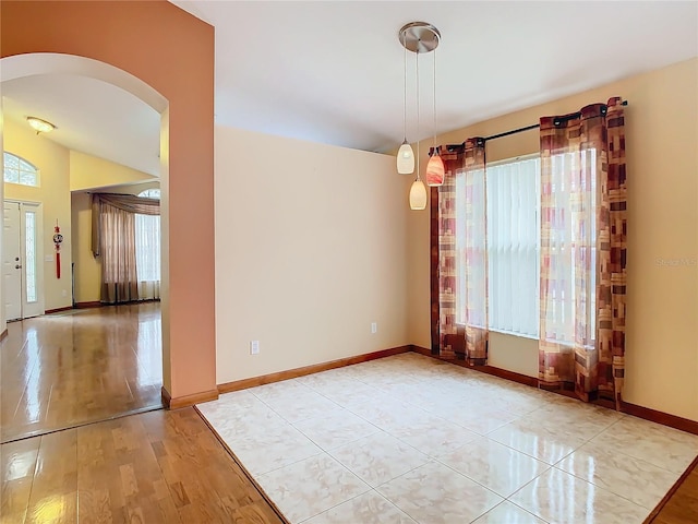 spare room featuring light wood-type flooring and lofted ceiling