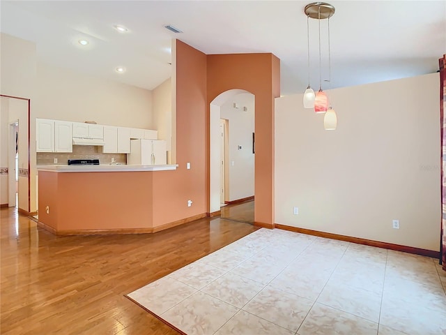 kitchen with white refrigerator, pendant lighting, white cabinets, light hardwood / wood-style flooring, and stove