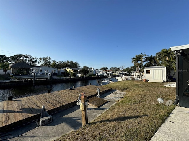 view of dock with a lawn and a water view