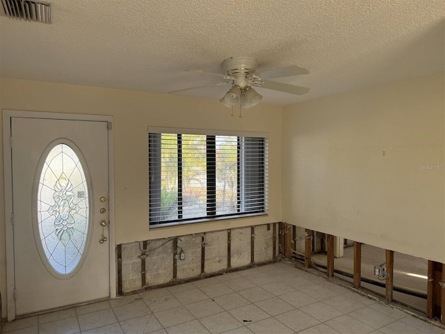 tiled entryway featuring a textured ceiling, ceiling fan, and a healthy amount of sunlight