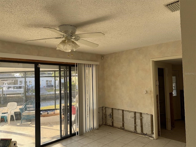 tiled spare room with ceiling fan and a textured ceiling