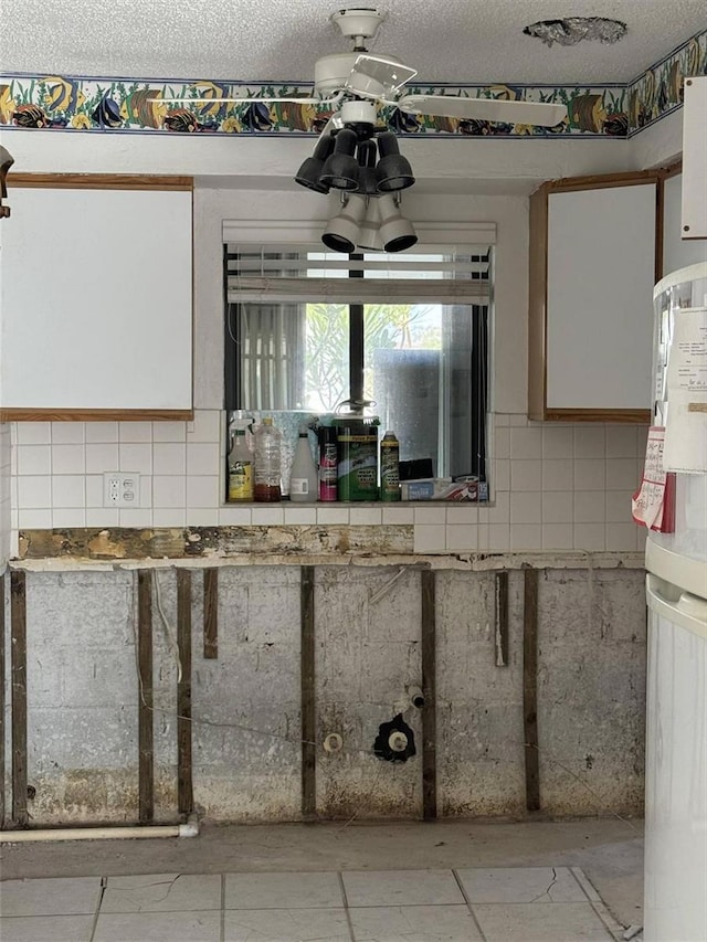 kitchen featuring a textured ceiling, tasteful backsplash, and white cabinetry