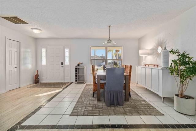 tiled dining room with plenty of natural light and a textured ceiling