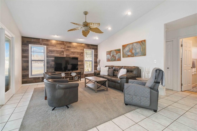 living room featuring ceiling fan, wooden walls, vaulted ceiling, and light tile patterned floors