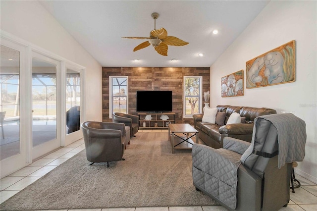 tiled living room with french doors, ceiling fan, wooden walls, and vaulted ceiling