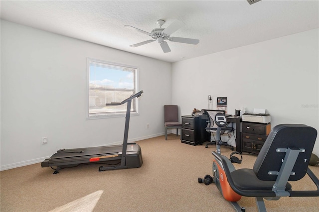 exercise room featuring ceiling fan, light colored carpet, and a textured ceiling