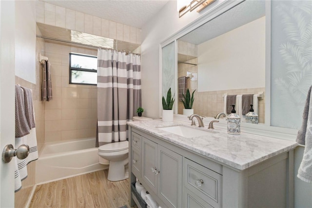 full bathroom featuring hardwood / wood-style floors, vanity, toilet, a textured ceiling, and shower / bath combo with shower curtain