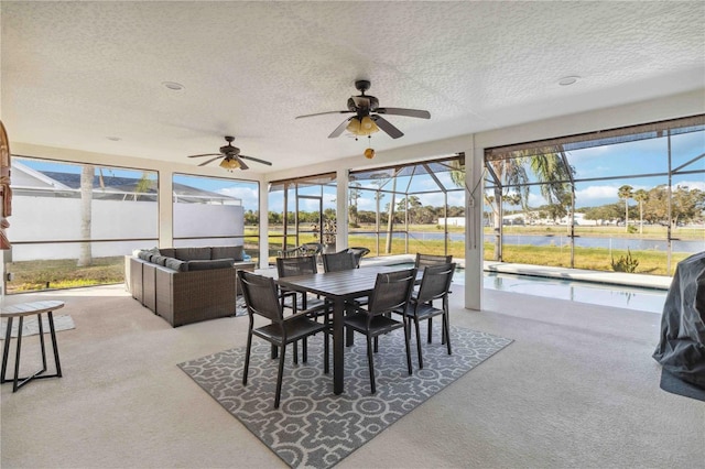 sunroom featuring a pool, ceiling fan, and a water view