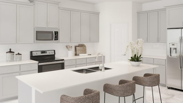 kitchen featuring sink, an island with sink, a breakfast bar area, decorative backsplash, and appliances with stainless steel finishes