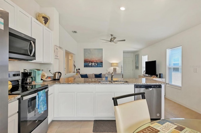 kitchen featuring sink, white cabinetry, kitchen peninsula, light stone countertops, and appliances with stainless steel finishes