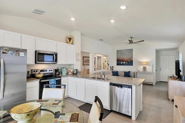 kitchen featuring stainless steel appliances, white cabinetry, sink, and light stone countertops