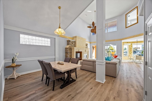 dining area with high vaulted ceiling, decorative columns, and light hardwood / wood-style flooring