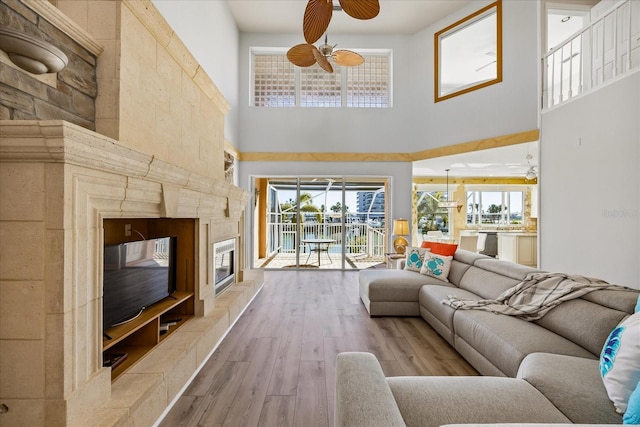 living room with a healthy amount of sunlight, a fireplace, light hardwood / wood-style floors, and a high ceiling