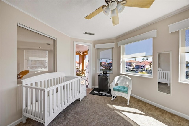 carpeted bedroom featuring a nursery area and ceiling fan