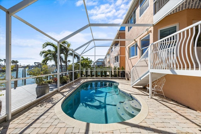 view of pool featuring a lanai, a patio area, and a water view