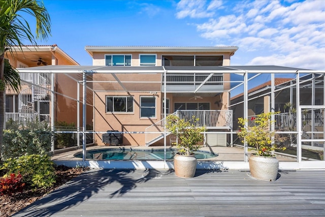 rear view of house with a balcony, a jacuzzi, ceiling fan, glass enclosure, and a patio area