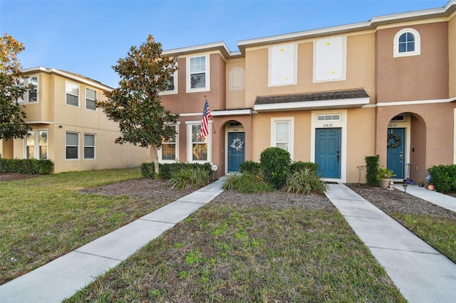 townhome / multi-family property featuring a front lawn