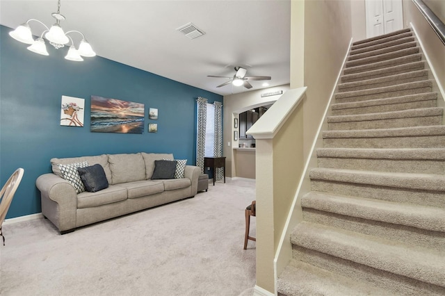 carpeted living room with ceiling fan with notable chandelier