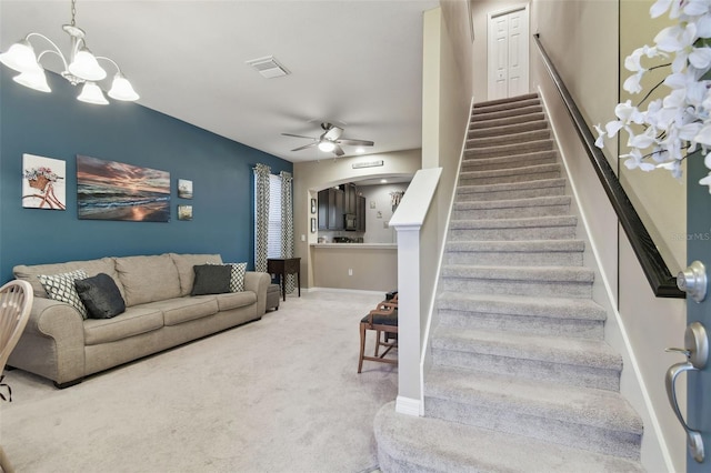 staircase featuring carpet floors and ceiling fan with notable chandelier