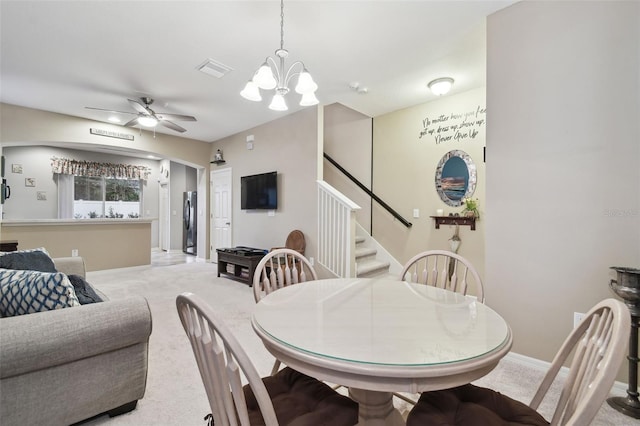 dining room featuring light colored carpet and ceiling fan with notable chandelier