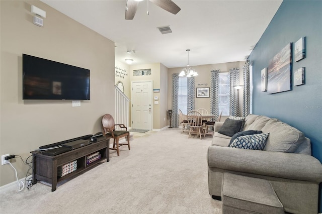 living room featuring ceiling fan with notable chandelier and light colored carpet