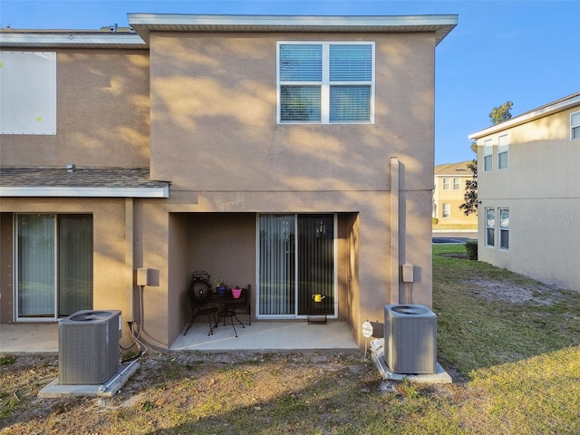 rear view of property featuring central AC unit, a patio area, and a lawn