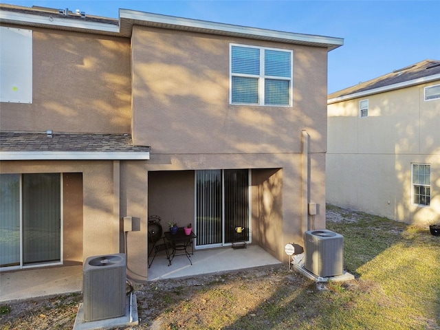 back of property featuring central AC unit, a lawn, and a patio