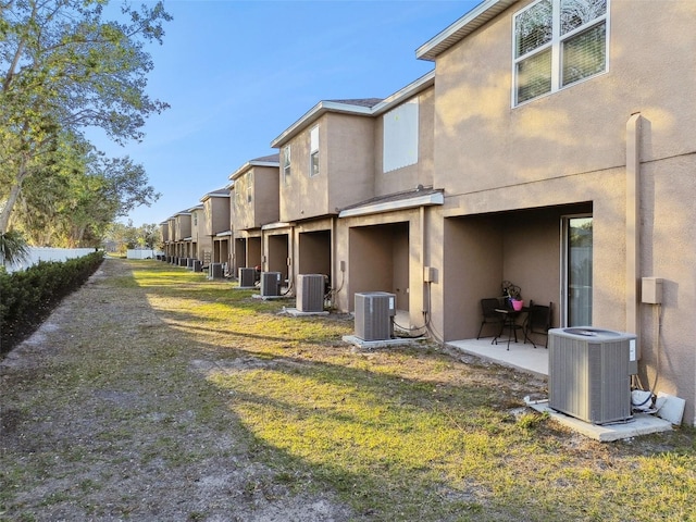 rear view of property with a patio area, central AC unit, and a lawn