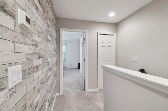 corridor featuring light colored carpet and brick wall