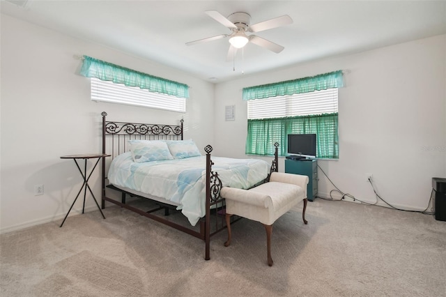 bedroom with multiple windows, ceiling fan, and light carpet