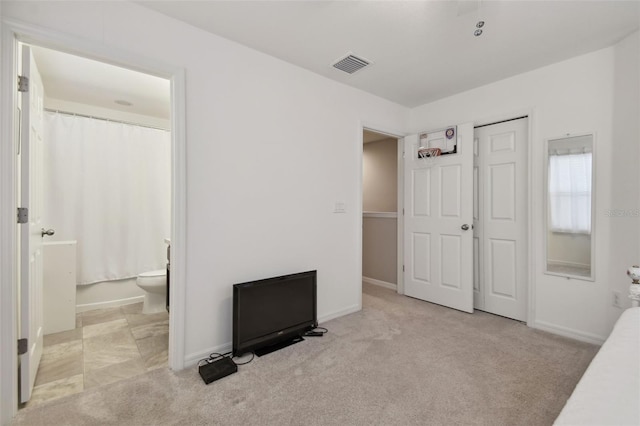 unfurnished bedroom featuring ensuite bathroom and light colored carpet