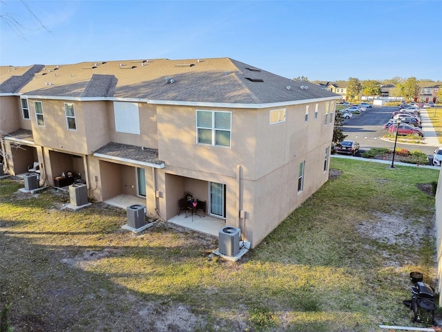 rear view of house featuring a patio, central AC unit, and a lawn